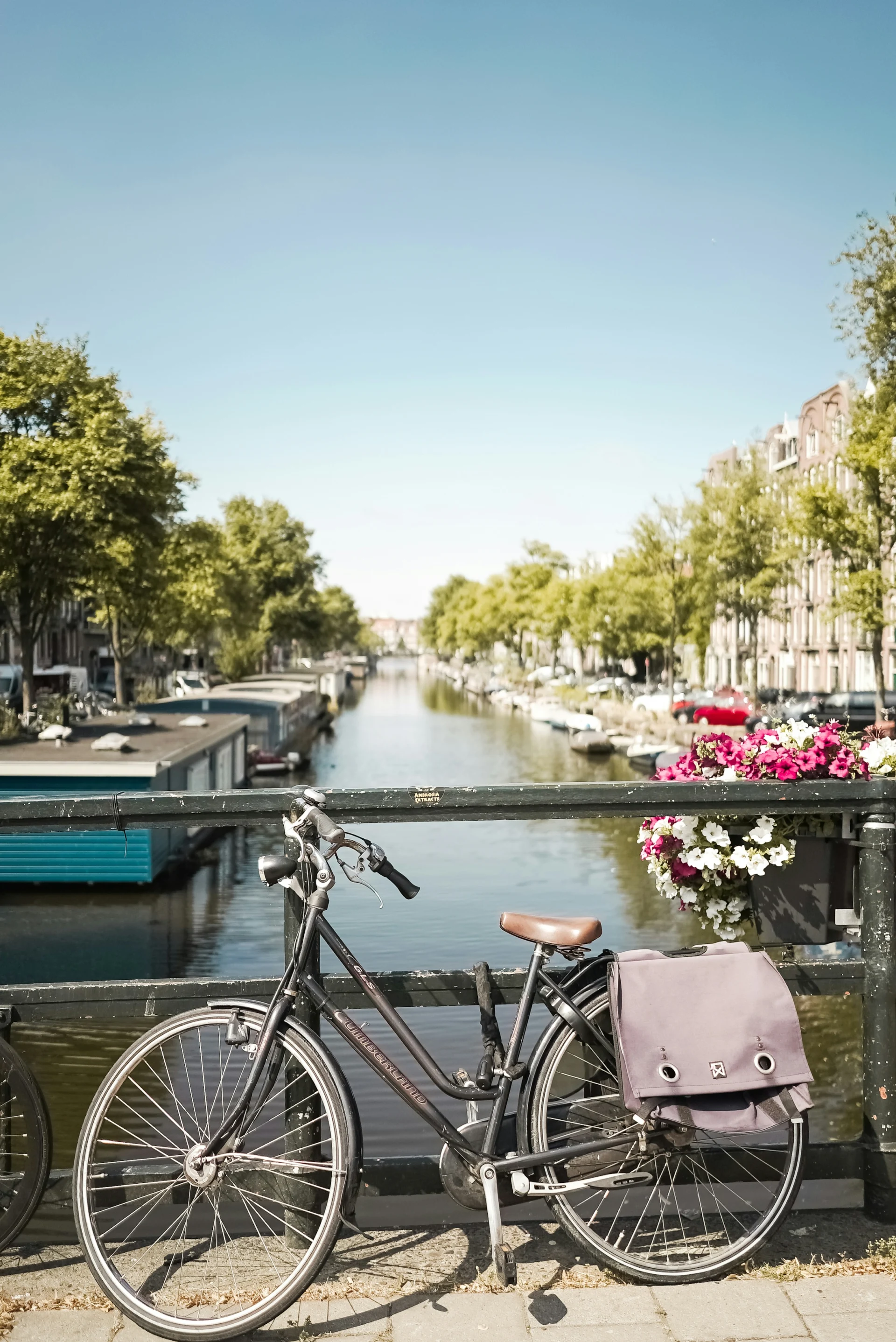 A bicycle parked on a bridge railing over an Amsterdam canal