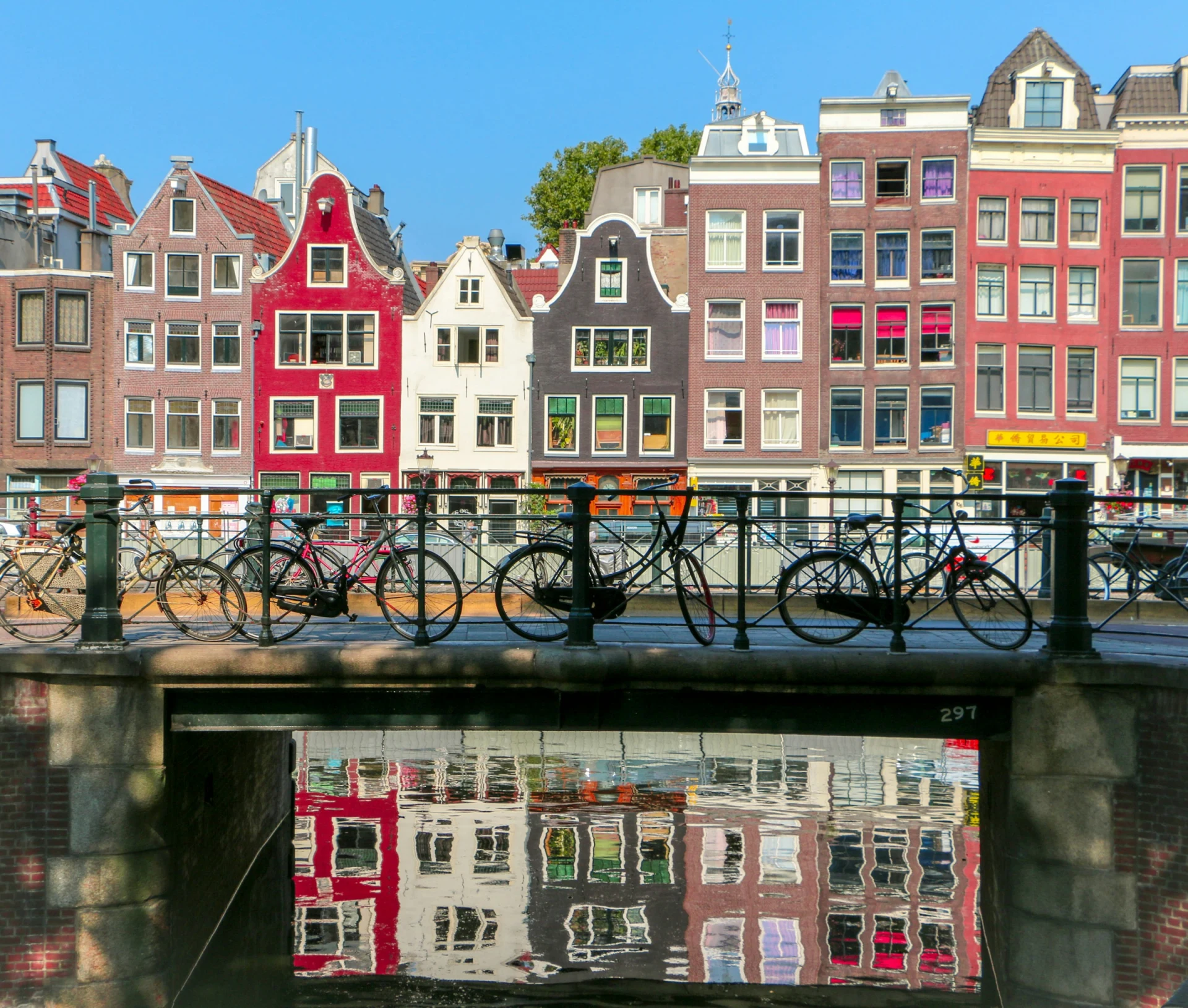 Colourful gabled canal houses with bicycles on a bridge